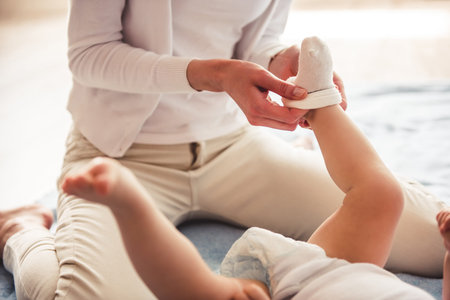 Cropped image of beautiful mom putting on her cute baby socks