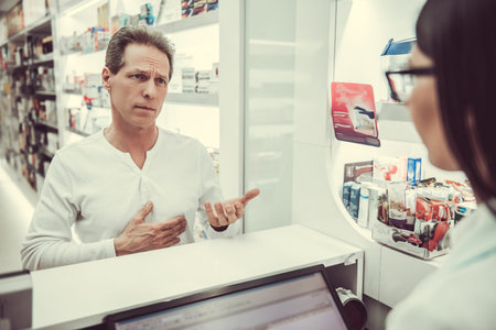 At the pharmacy. Handsome client is talking to a beautiful female pharmacist at the cash deskの写真素材