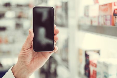 At the pharmacy. Cropped image of man holding a smart phoneの写真素材