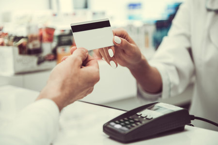 At the pharmacy. Cropped image of young female pharmacist taking a credit card from a client while...