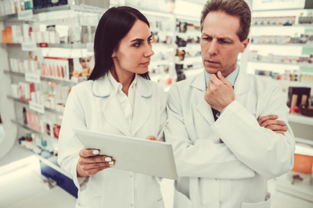 Beautiful pharmacists are using a digital tablet while working in pharmacyの写真素材