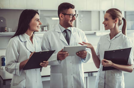 Beautiful medical doctors are using a digital tablet, discussing test results and smiling while working at the labの写真素材