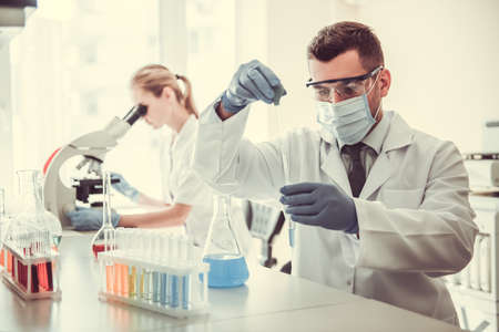 Beautiful medical doctors are working with test tubes and microscope at the labの写真素材