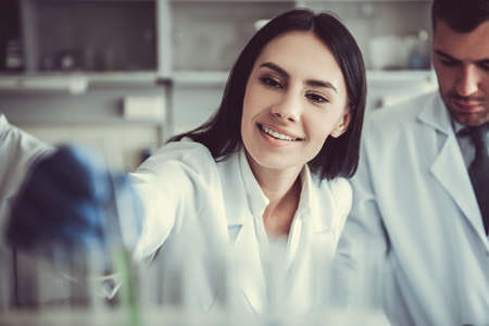 Beautiful medical doctors in gloves are working with test tubes at the labの写真素材