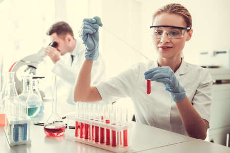 Beautiful medical doctors are working with test tubes and microscope at the labの写真素材