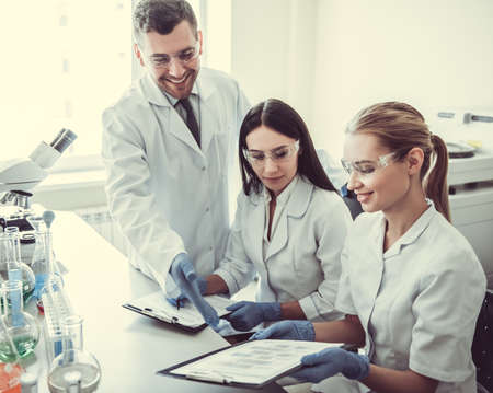 Beautiful medical doctors in gloves and glasses are discussing test results while  working at the labの写真素材