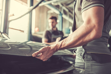 Handsome young auto mechanics in uniform are examining car while working in auto serviceの写真素材