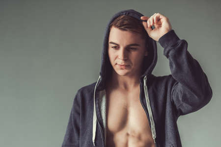 Handsome muscular sportsman is posing on gray backgroundの写真素材