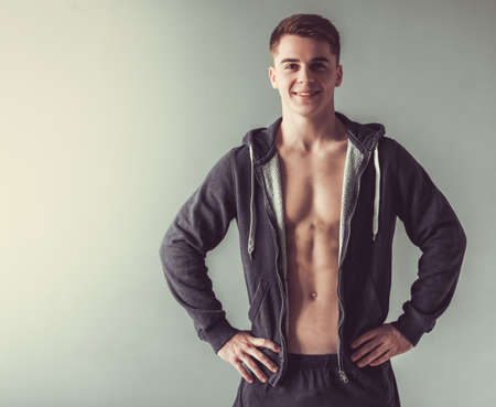 Handsome muscular sportsman is looking at camera and smiling, on gray backgroundの写真素材