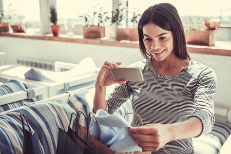 A young pretty girl sitting in a cafe looking at clothes on saleの写真素材