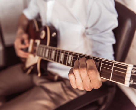 Cropped image of young businessman playing guitar in his office during the breakの写真素材