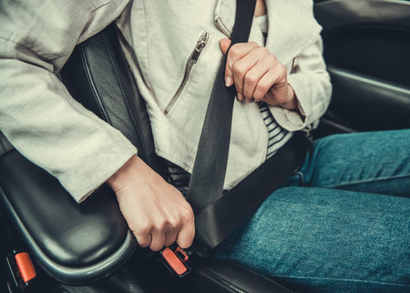 Cropped image of girl fastening a seat belt while driving a car