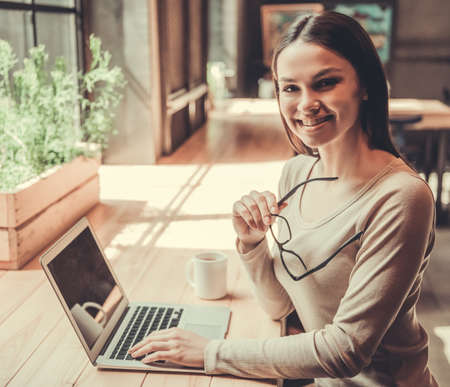 A young beautiful girl uses a laptop while working in her officeの写真素材