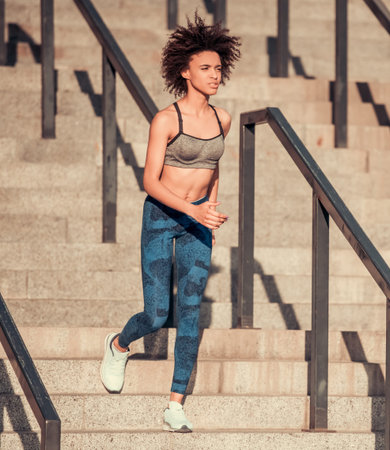 Beautiful Afro American girl in sportswear is running, full length