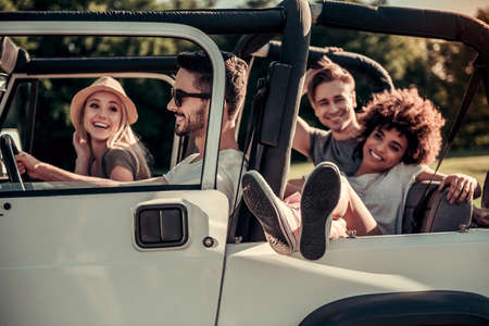 Happy young people are smiling while travelling by car in sunny weatherの写真素材