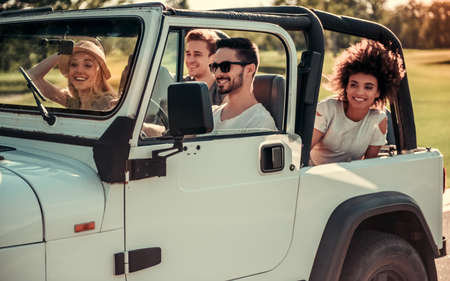 Happy young people are smiling while travelling by car in sunny weatherの写真素材