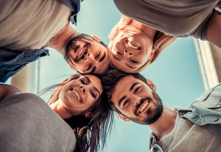 Bottom view of cheerful young people looking at camera and smiling while walking outdoorsの写真素材