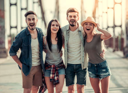 Cheerful young people are hugging, looking at camera and smiling while walking in the cityの写真素材