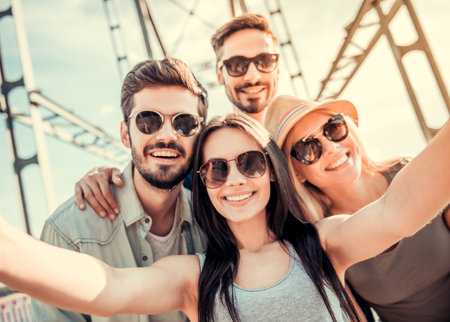 Cheerful young people are doing selfie, looking at camera and smiling while walking outdoorsの写真素材
