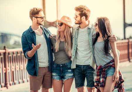 Cheerful young people are hugging, talking and smiling while walking in the cityの写真素材