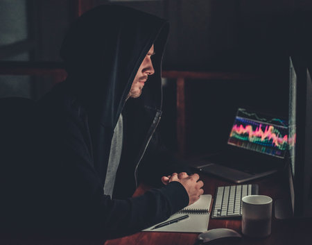 Handsome young man in hoodie is working with a computer at night