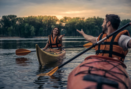 Happy young couple in sea vests is smiling while sailing kayaksの写真素材
