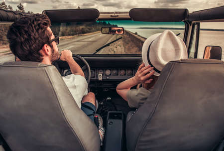 Back view of beautiful young couple travelling by carの写真素材