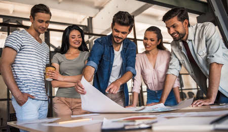 Beautiful young business people in casual clothes are discussing work and smiling at the conference in officeの写真素材
