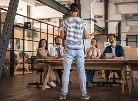 Beautiful young business people in casual clothes are discussing work and smiling at the conference in officeの写真素材