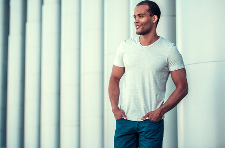 Portrait of handsome Afro American man looking away and smiling while walking in cityの写真素材