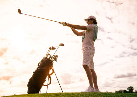 Full length portrait of handsome man choosing a golf club while standing on golf courseの写真素材