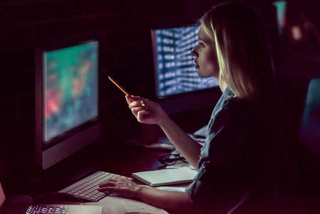 Beautiful young business woman is working with computer in office at nightの写真素材