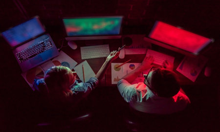 Top view of beautiful young businessman and woman working with computer in office at night