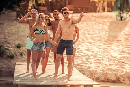 Happy friends are talking and smiling while walking along the pier at the seaの写真素材