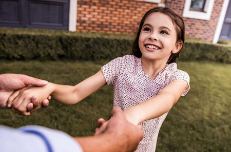 Cute little girl and her is smiling while spinning with her dad outdoorsの写真素材