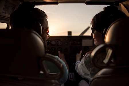 Back view from the inside of the plane, couple in aviation headsets is ready to flyの写真素材