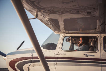 Beautiful couple in aviation headsets is sitting in aircraft ready to flyの写真素材