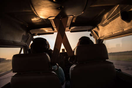 Back view from the inside of the plane, couple in aviation headsets is ready to flyの写真素材