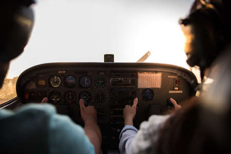 Back view from the inside of the plane, couple in aviation headsets is ready to flyの写真素材