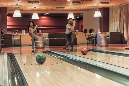 Happy young friends are having fun while playing bowling togetherの写真素材