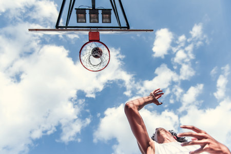 Bottom view of basketball player shooting a ball through the hoop while playing on basketball court...