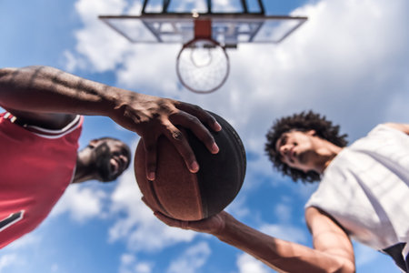 Bottom view of handsome basketball players playing on basketball court outdoorsの写真素材