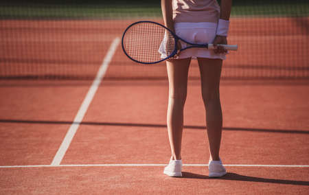 Cropped image of girl holding tennis racket while playing tennis on court outdoorsの写真素材