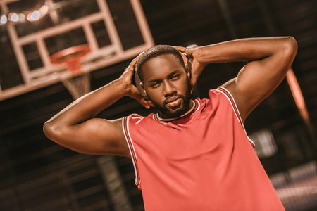 Handsome Afro American basketball player is playing basketball outdoors in the eveningの写真素材