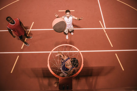 High angle view of handsome guys playing basketball outdoors at nightの写真素材