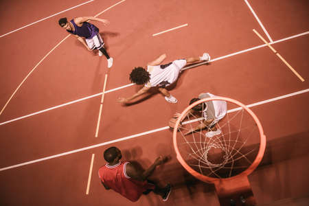 High angle view of handsome guys playing basketball outdoors at nightの写真素材