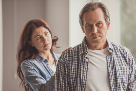 Beautiful wife is calming her husband who is looking at camera