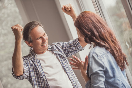 Happy couple at home. Handsome mature man is feeling happy while talking to his wifeの写真素材