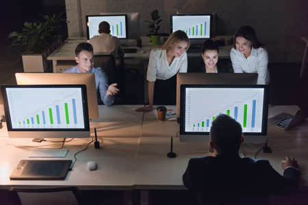 Successful business people are using computers and smiling while working in office late at nightの写真素材