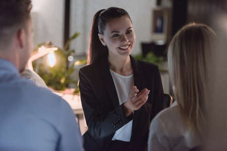 Successful business people are sitting in circle and discussing affairs while working in office late at nightの写真素材